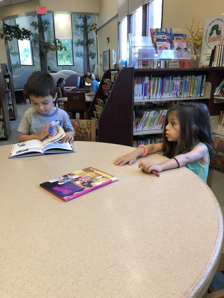Two siblings reading together at the library