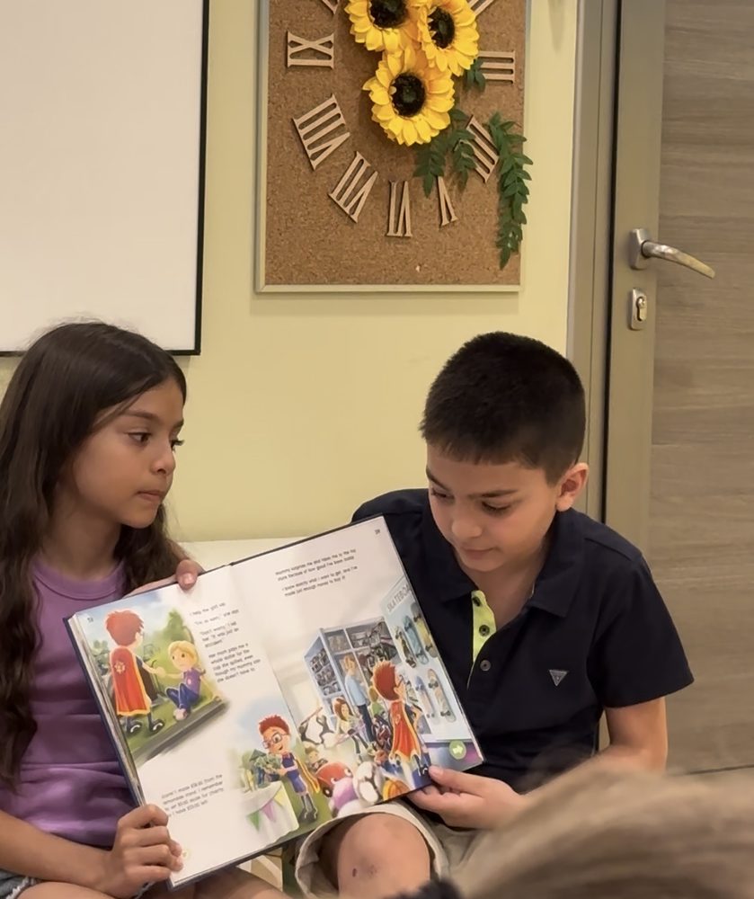 Reading a picture book aloud to a younger child at a book club session